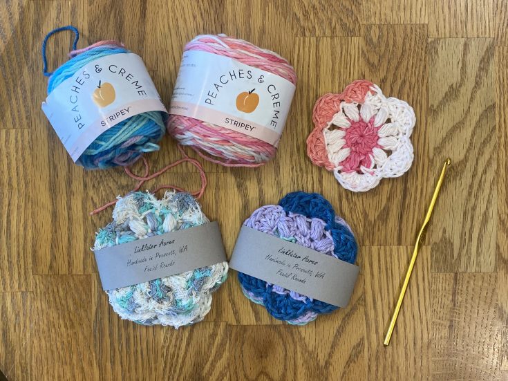 2 skeins of yarn with 3 scrubbies on a table